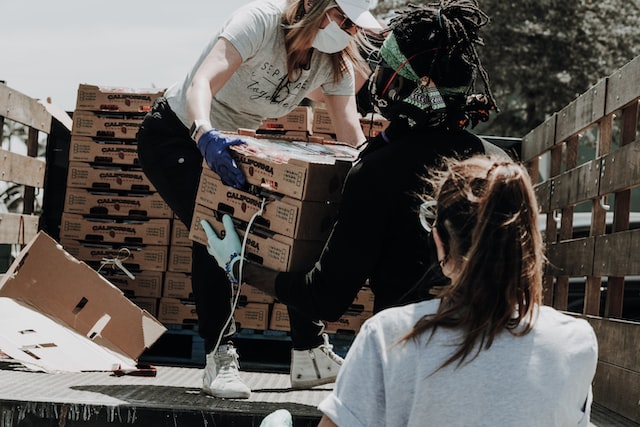 people doing charity work unloading crates of food from a van